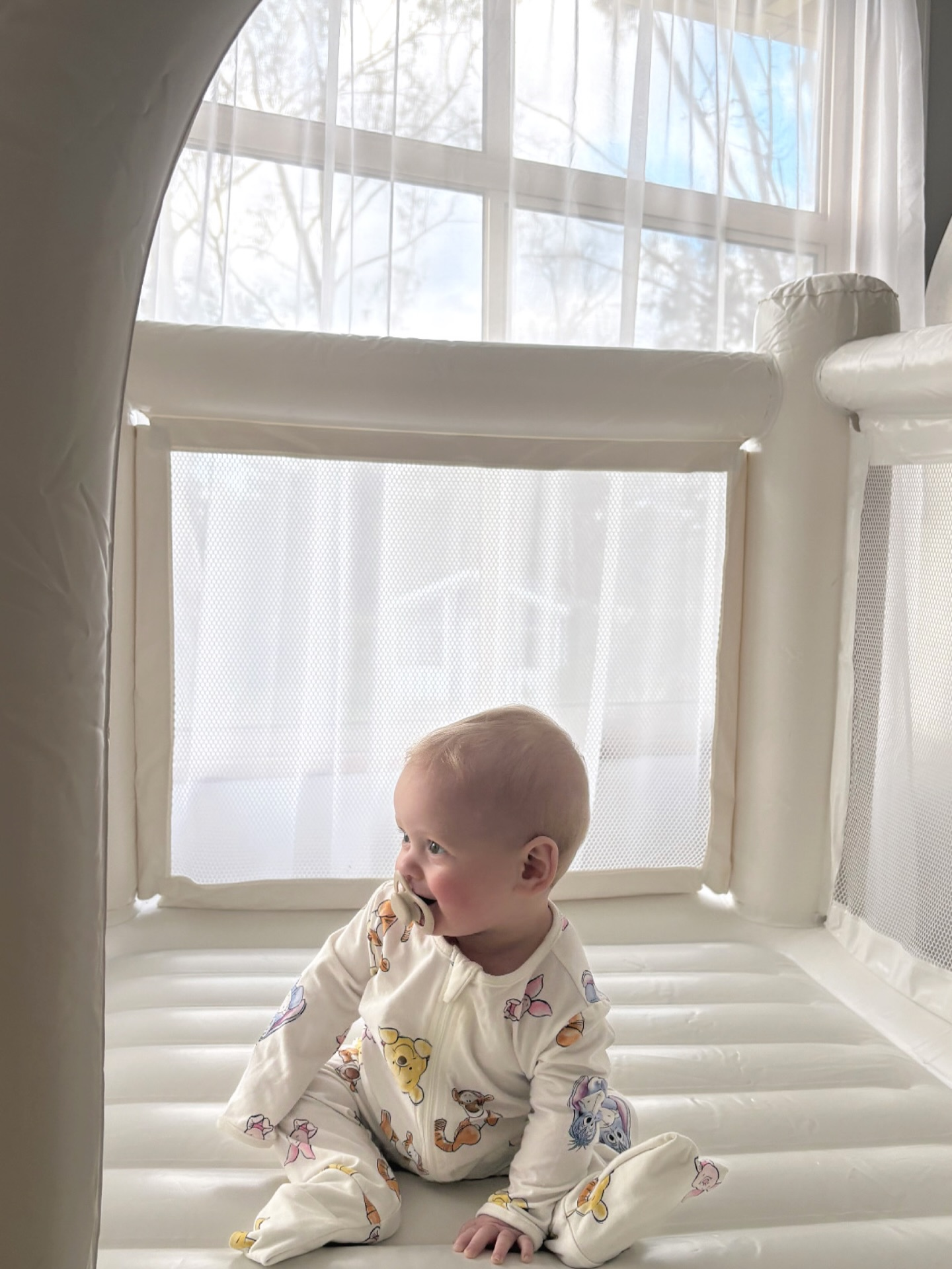 Baby smiling inside a white bounce house at a KloudKoCollective soft play hire setup